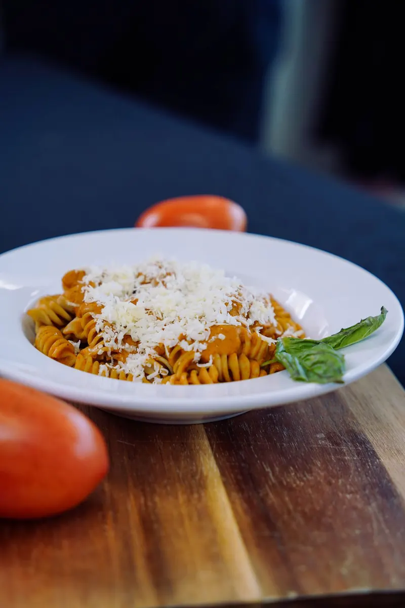 Bowl of rotini in red sauce under grated parmesan, shot for the CSMP feed