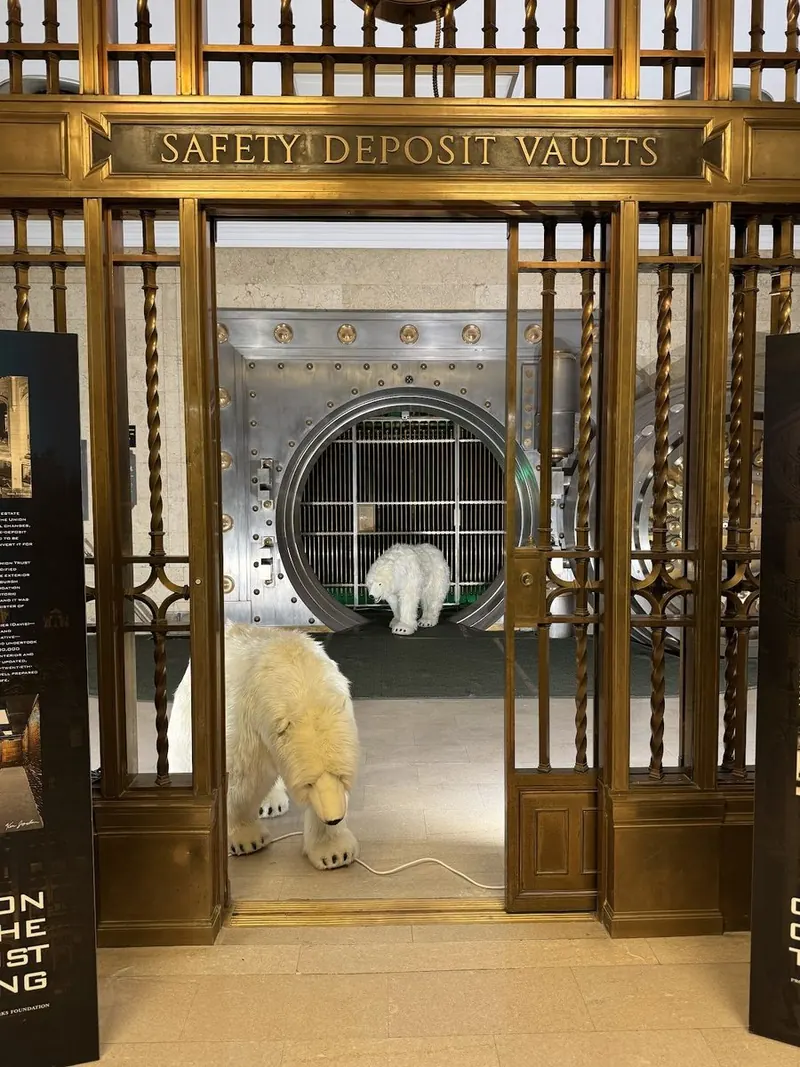 A polar bear figure peeking through the brass vault gates for National Polar Bear Day