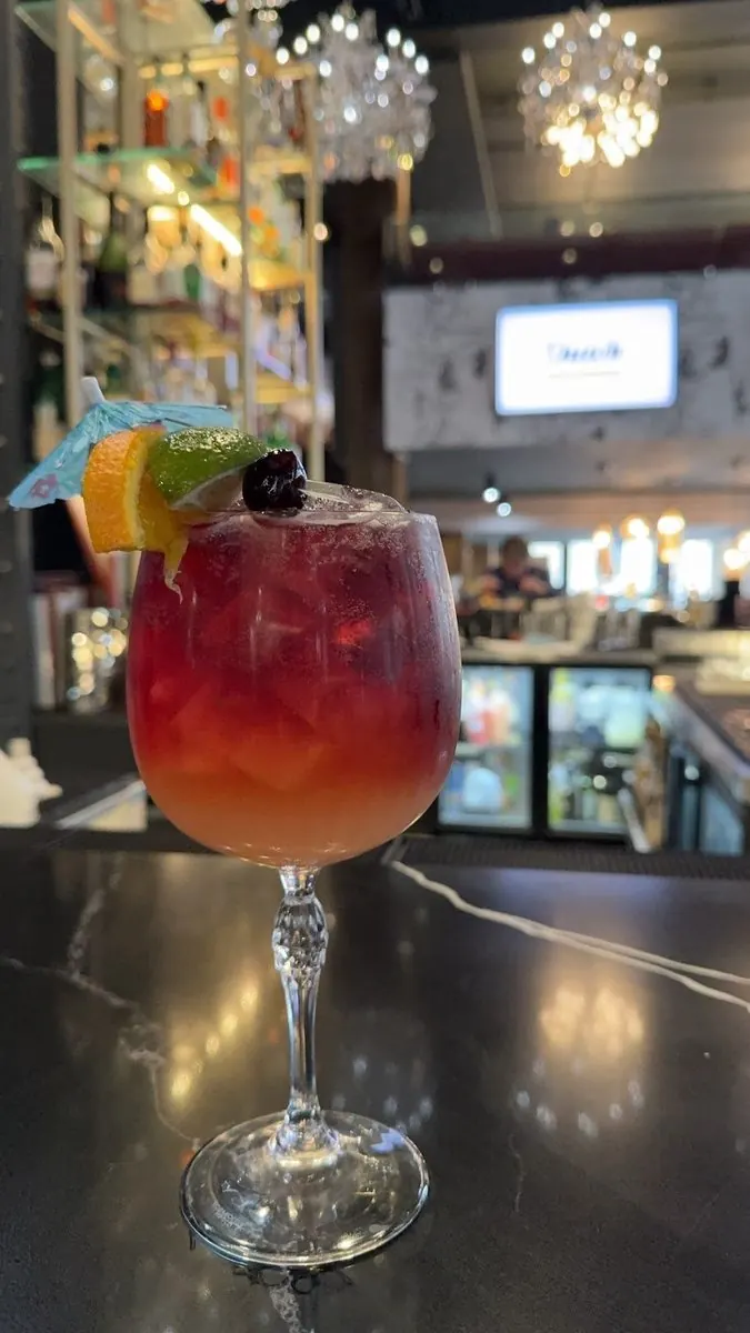 Red cocktail on the lobby bar with chandelier light behind it