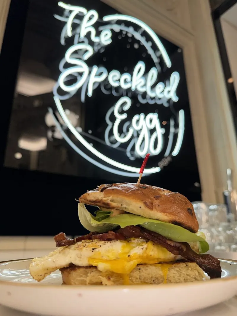 Breakfast sandwich under The Speckled Egg neon sign