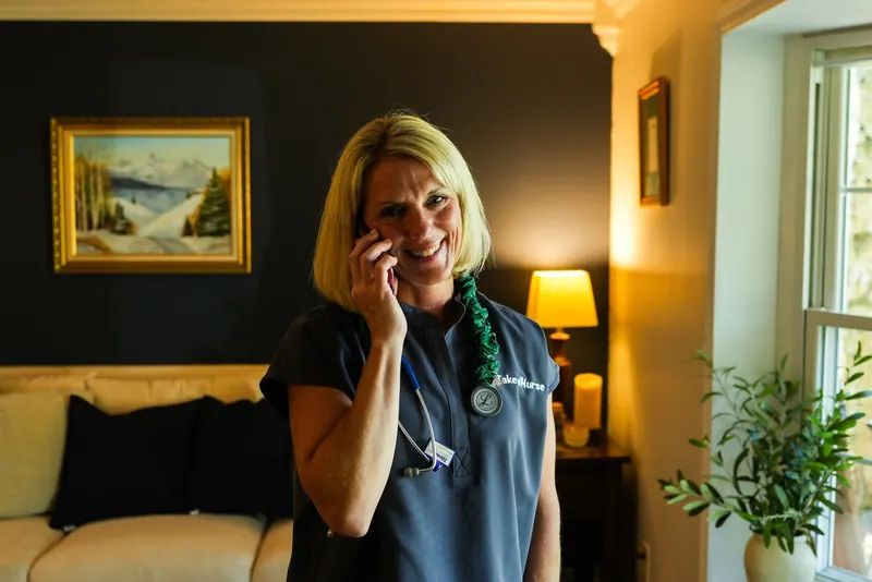 Kathy Fadgen takes a call in a lamp-lit living room, stethoscope around her neck