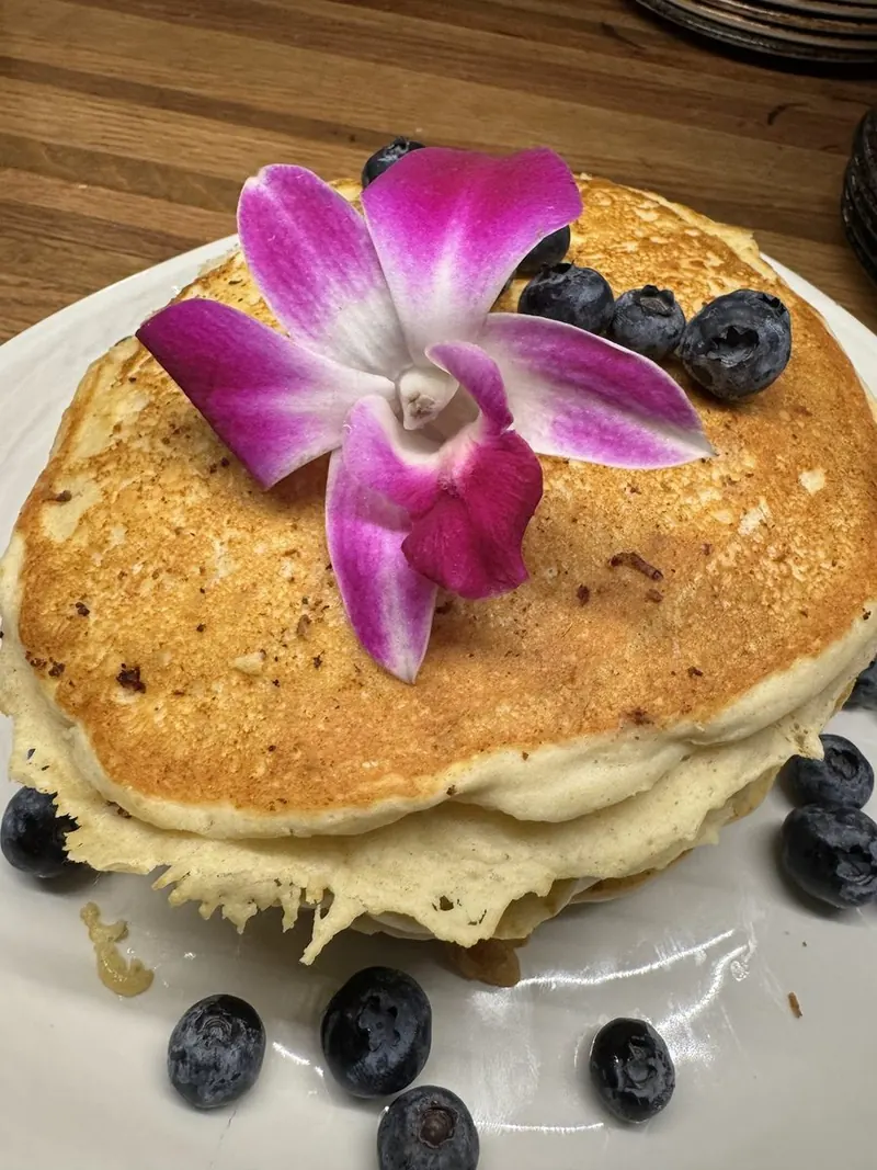 Pancake stack with berries and an orchid