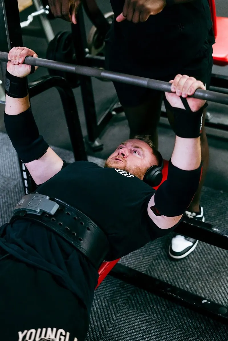 Trainer spotting a member on the bench press