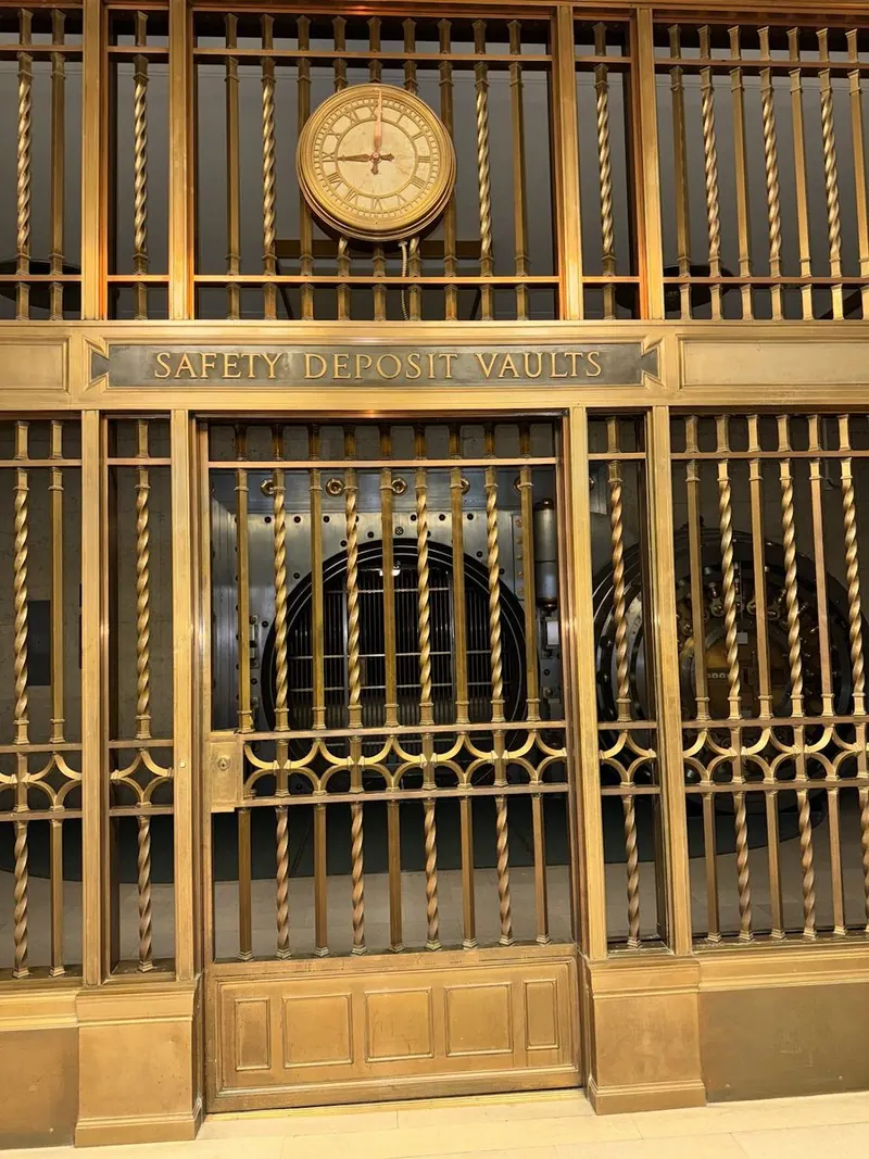 Bronze safe deposit vault gate with a clock above it
